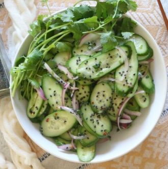 Asian Cucumber Salad - Thinly sliced cucumbers and red onions tossed with a white wine vinaigrette dressing makes a light and refreshing salad. Top with rich black sesame seeds for major flavor action. Paleo & Whole 30 Compliant.