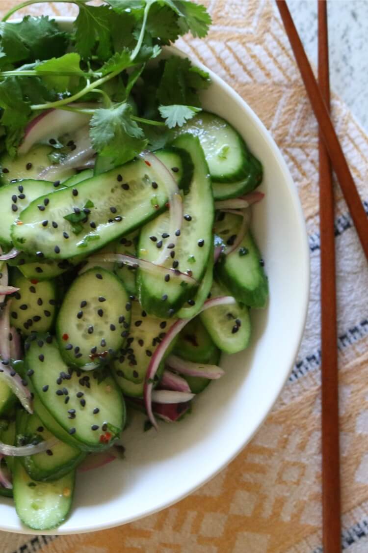 Asian Cucumber Salad - Thinly sliced cucumbers and red onions tossed with a white wine vinaigrette dressing makes a light and refreshing salad. Top with rich black sesame seeds for major flavor action. Paleo & Whole 30 Compliant. 