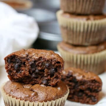 Flourless muffins stacked on top of each other and one is half eaten.