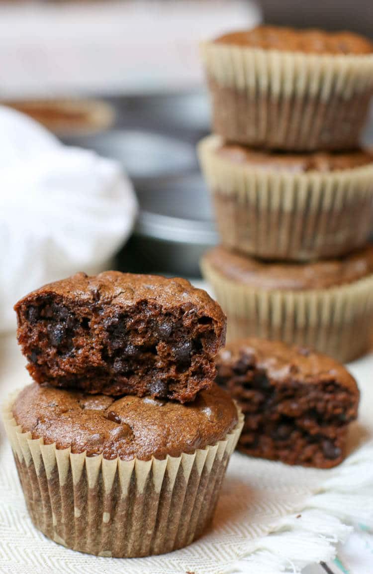 Flourless muffins stacked on top of each other and one is half eaten. 