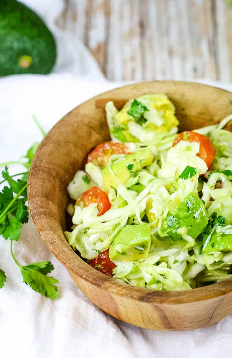 The BEST Avocado Cabbage Slaw - crunchy raw cabbage, seasonal tomatoes and creamy avocados make the best slaw. It's paleo, whole30 and keto too! #lowcarb #rawcabbage