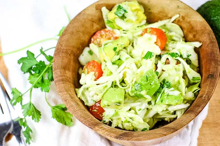 The BEST Avocado Cabbage Slaw - crunchy raw cabbage, seasonal tomatoes and creamy avocados make the best slaw. It's paleo, whole30 and keto too! #lowcarb #rawcabbage