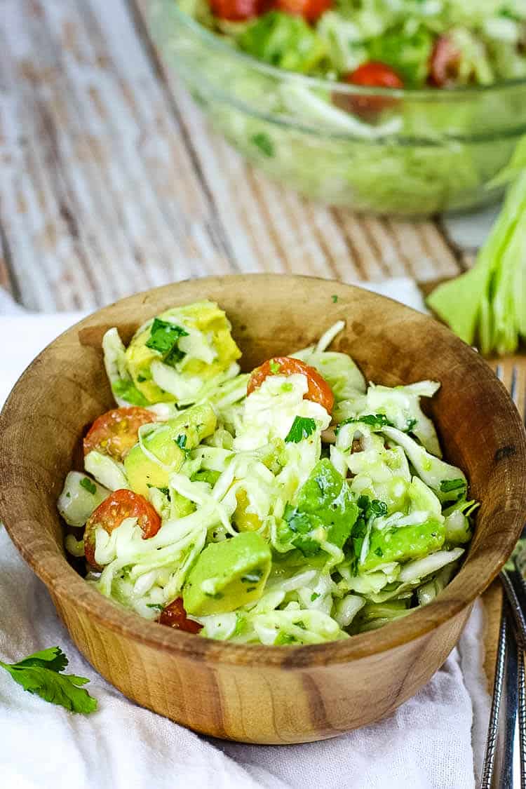 The BEST Avocado Cabbage Slaw - crunchy raw cabbage, seasonal tomatoes and creamy avocados make the best slaw. It's paleo, whole30 and keto too! #lowcarb #rawcabbage