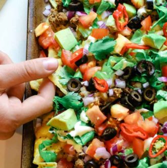 Sheet pan nachos with tortilla chips, taco meat and toppings.