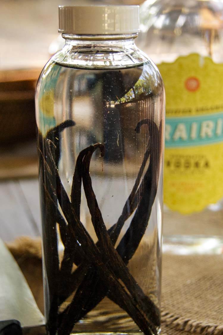 Vanilla beans in tall bottle with vodka poured over.