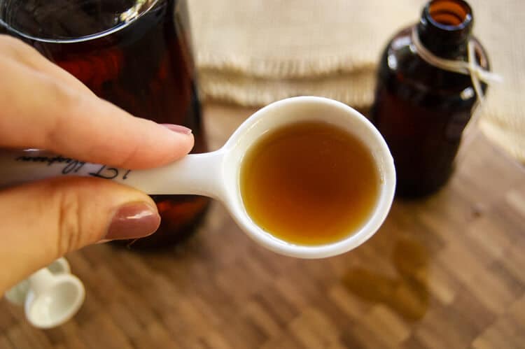 Vanilla bean extract on a spoon with a bottle next to it.