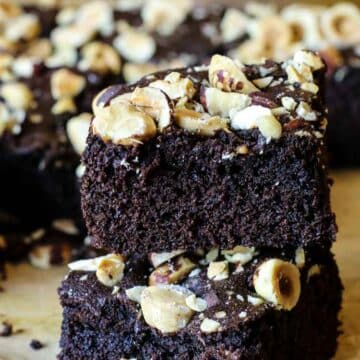 Two slices of coconut flour brownies with hazelnuts on top.