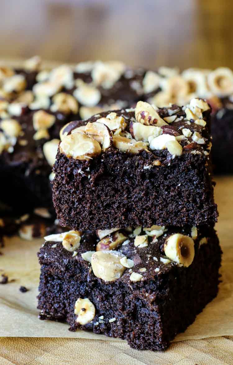 Two slices of coconut flour brownies with hazelnuts on top.