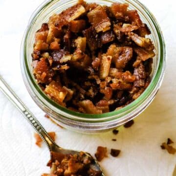 A jar with homemade bacon bits with a spoon loaded with bacon crumbles.