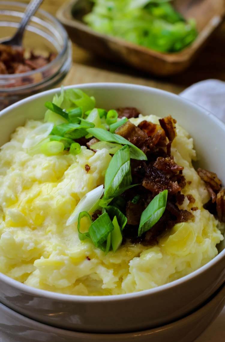 Mashed potatoes in a bowl with bacon bits and scallions.