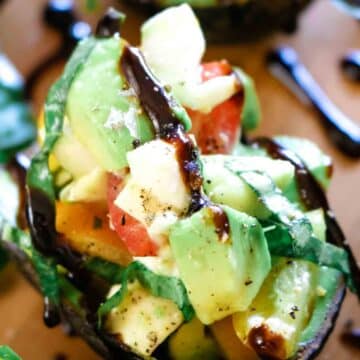 Caprese salad in an avocado shell drizzled with balsamic glaze.