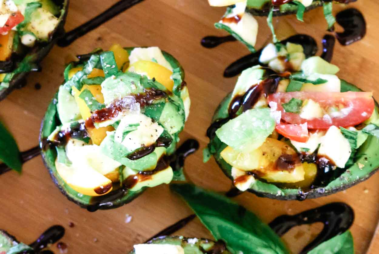 Caprese Stuffed Avocados with mozzarella and grape tomatoes and fresh basil.