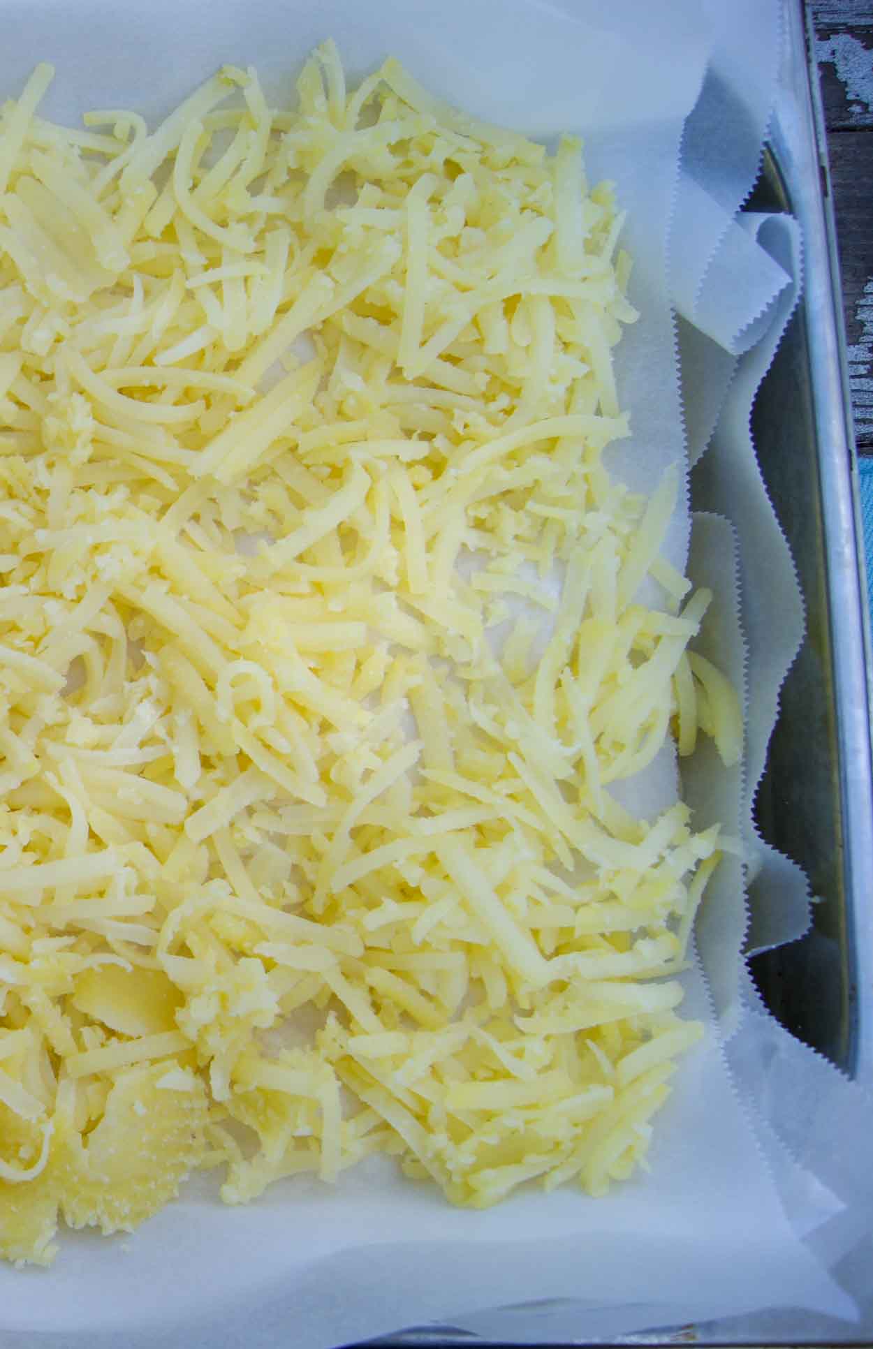 A large sheet with shredded parboiled potatoes ready to be flash frozen for hash browns.