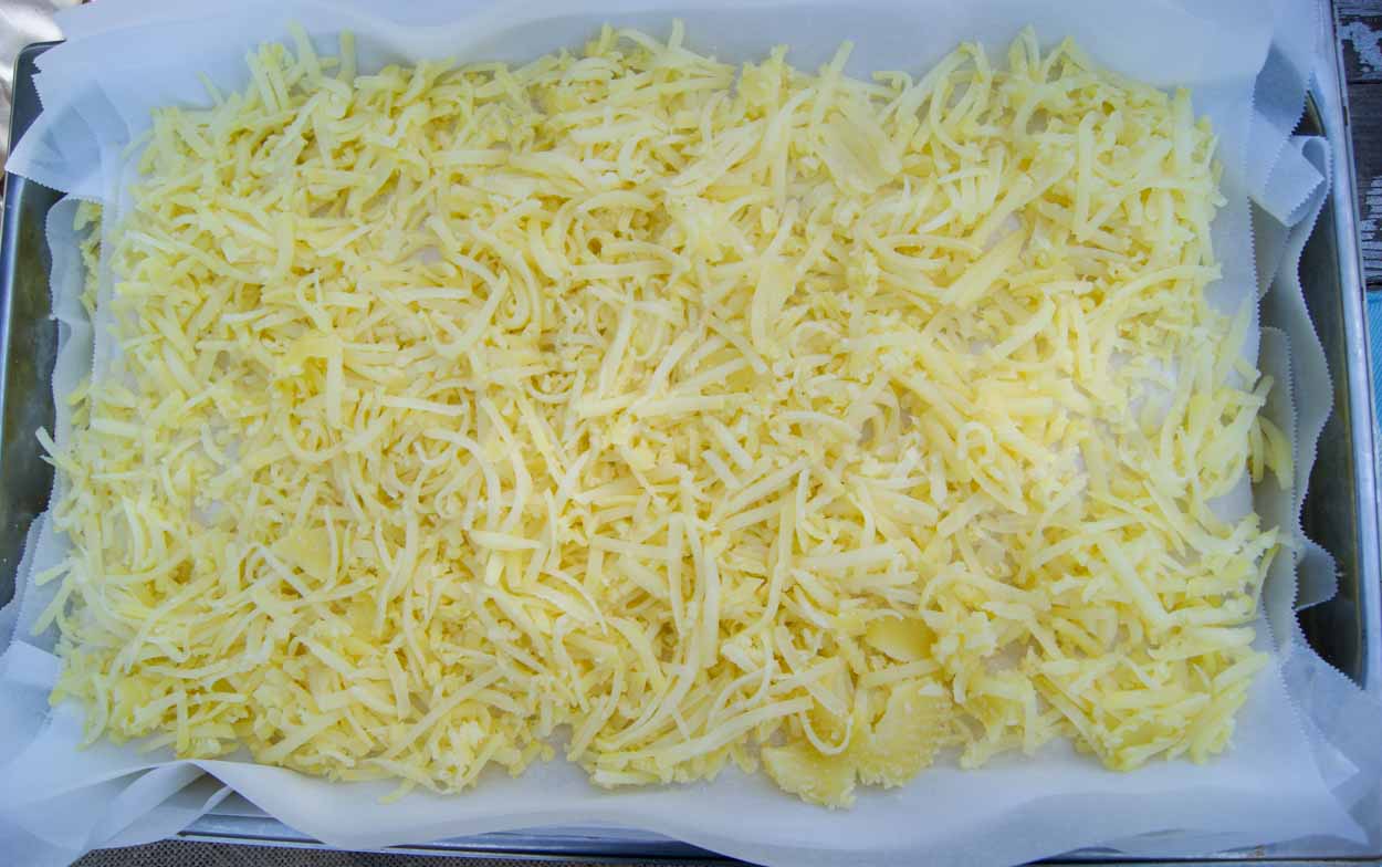 A large sheet with shredded parboiled potatoes ready to be flash frozen for hash browns.