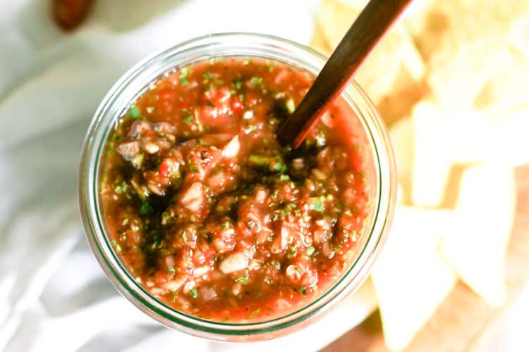 Overhead view of blender salsa with wooden spoon out of a glass jar