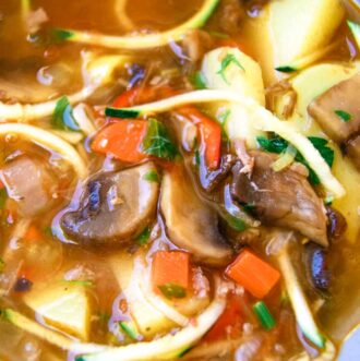 Bowl of healthy vegetable soup with zucchini noodles, potatoes and mushrooms.