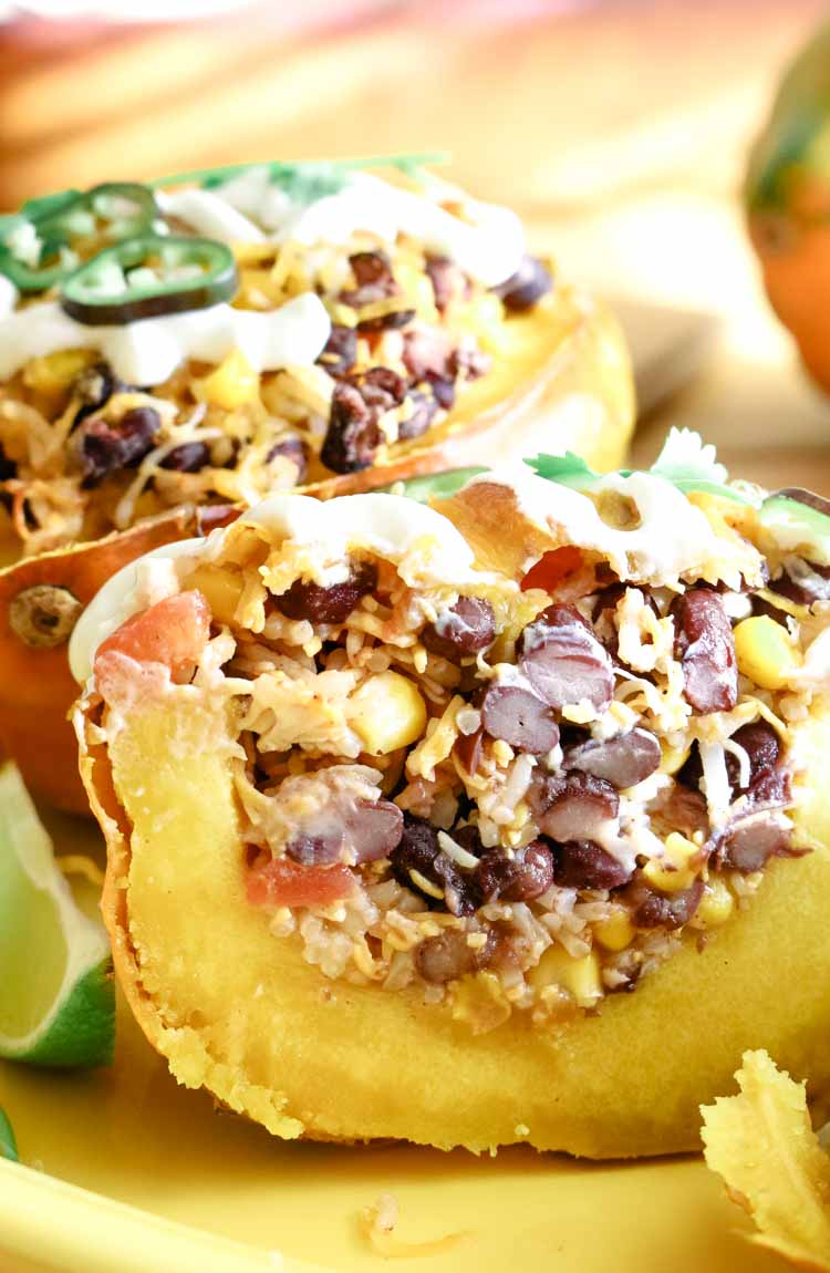 Rice, beans and corn stuffed acorn squash cut in half to expose stuffing.