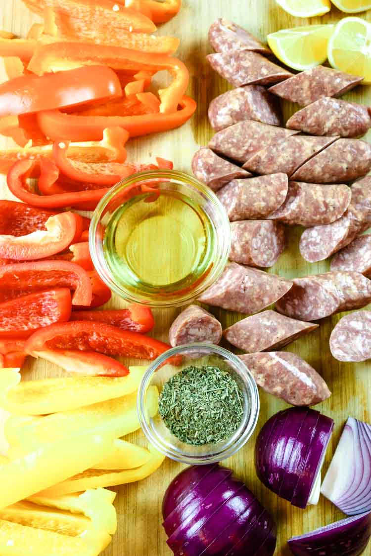 All ingredients for sheet pan sausage and peppers on a cutting board
