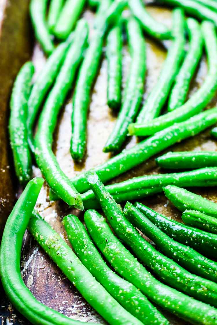 Seasoned raw green beans on a sheet pan