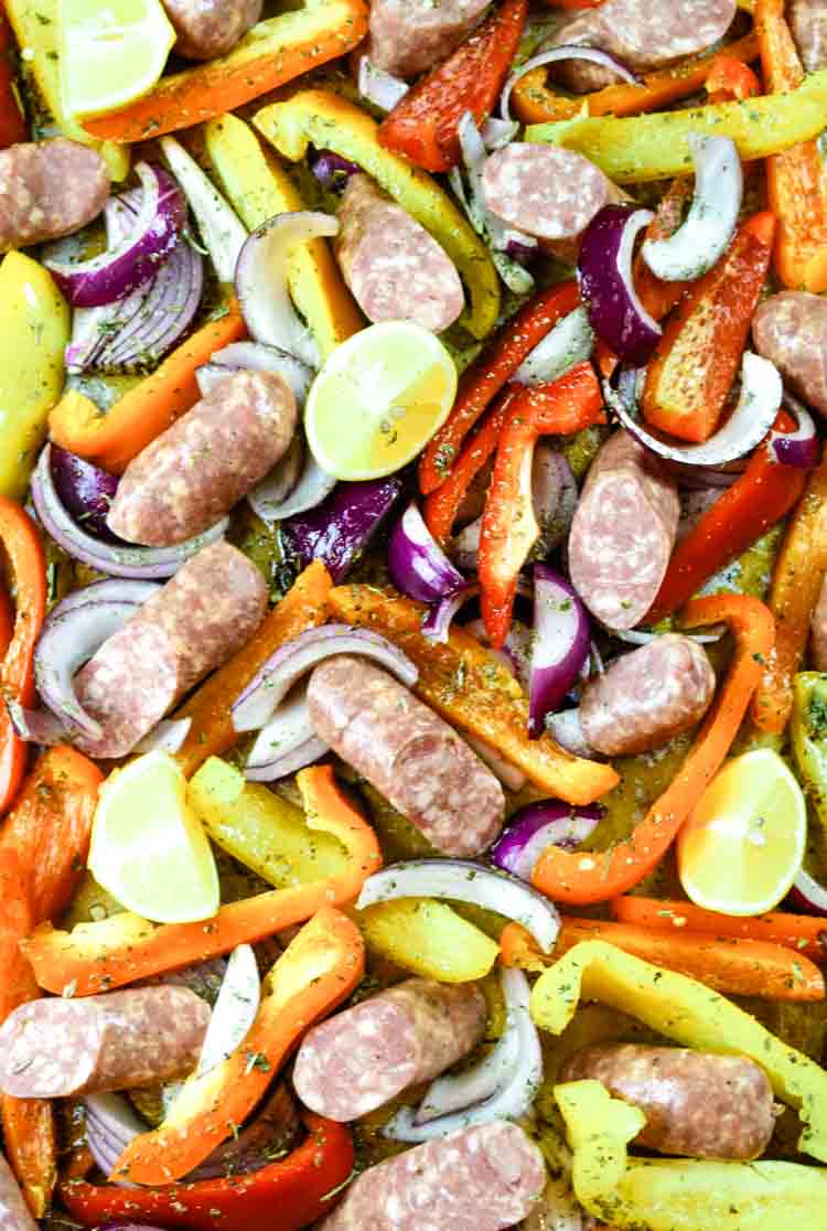 Sheet pan with sausages, bell peppers, onions ready to go into the oven