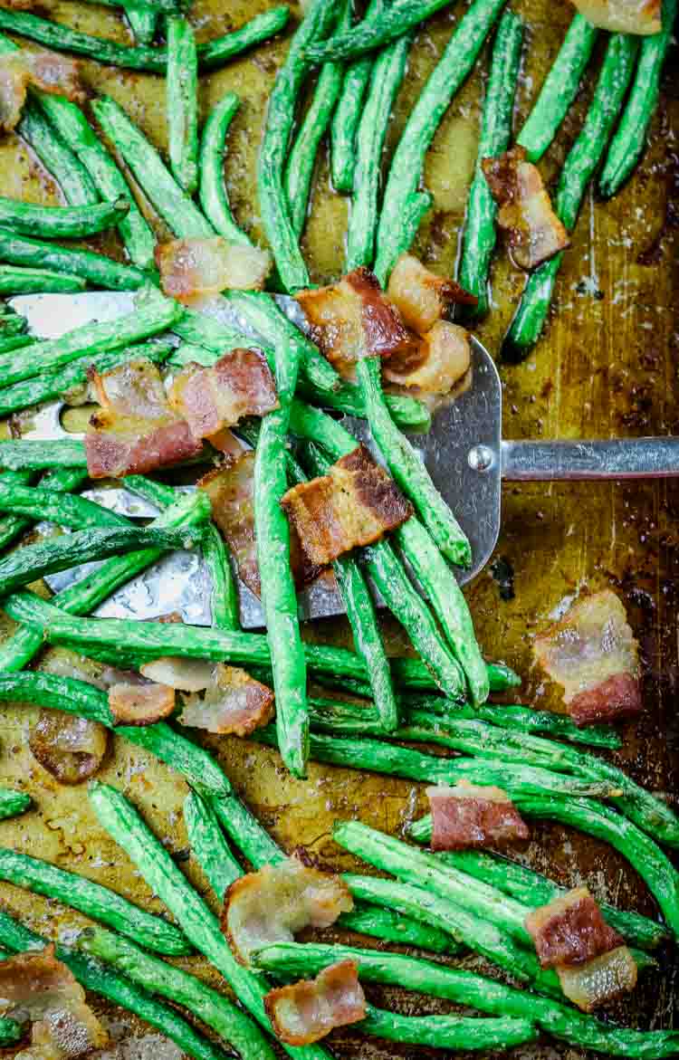 Oven raosted green beans and crunchy bacon on sheet pan with spatula