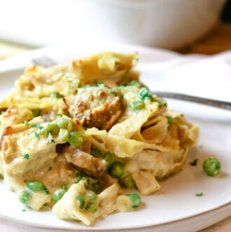 white plate with fork and single serving size of tuna casserole with peas and mushrooms