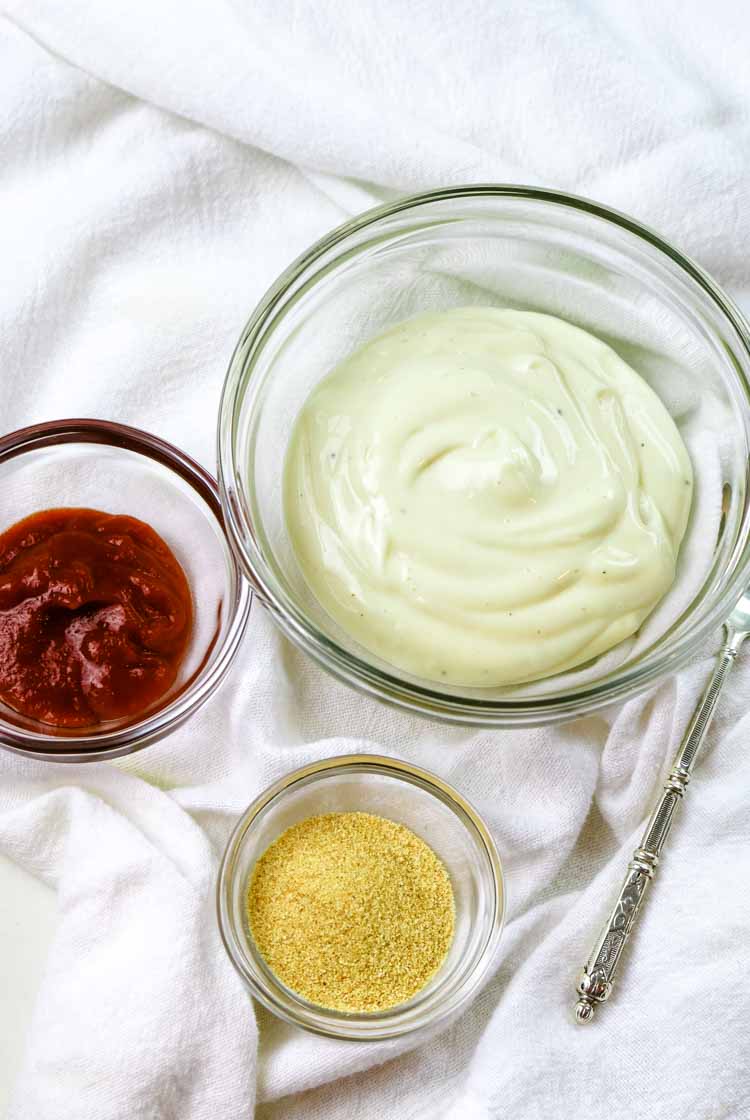Spicy mayo ingredients spread: small bowl of mayo, sriracha, and garlic powder with a spoon nearby