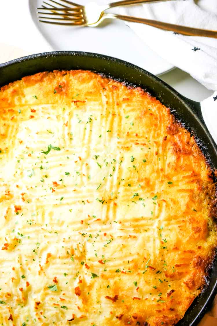 Shepherd's Pie in a cast iron skillet with ready plate and fork
