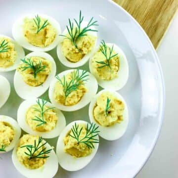 Deviled eggs on a platter and wooden cutting board.