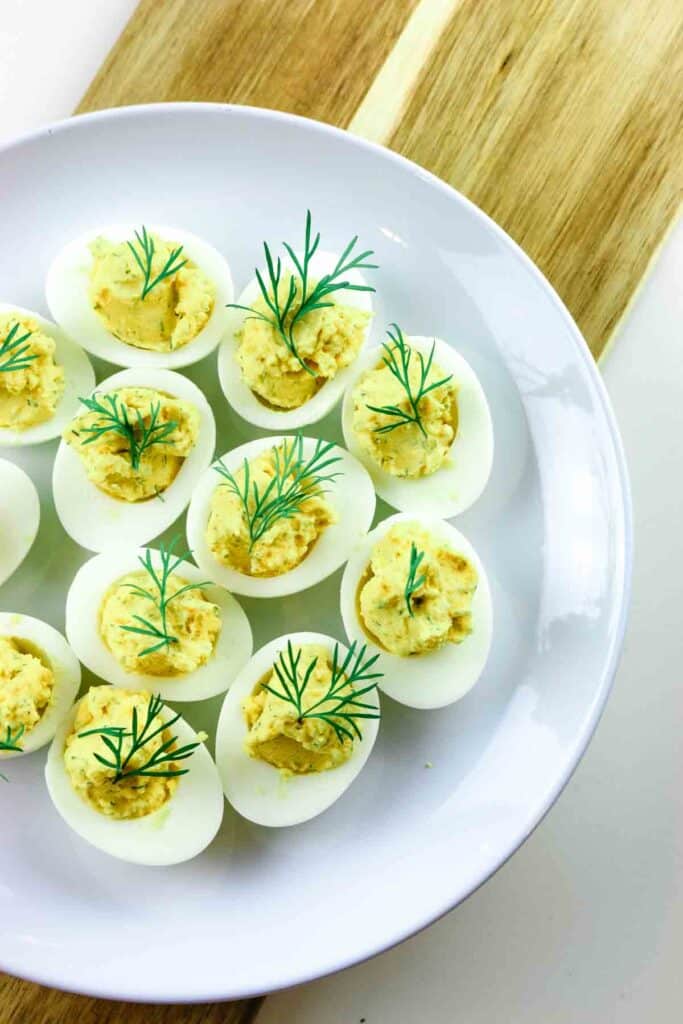 Deviled eggs on a platter and wooden cutting board.