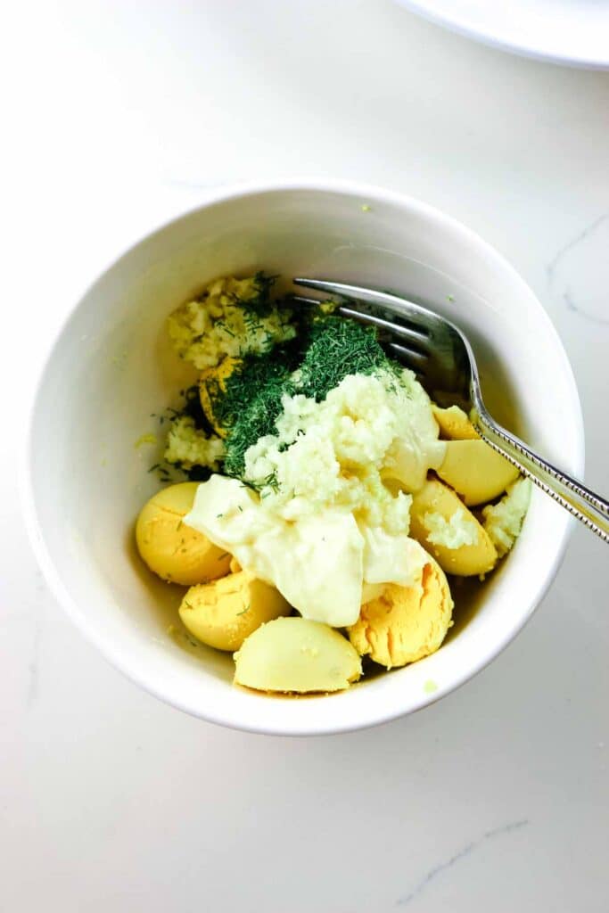 Egg yolks, mayonnaise, fresh garlic, and dill in a small ramekin.