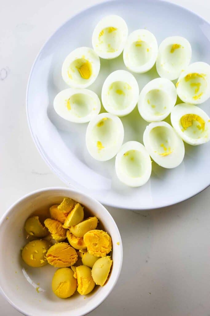 Cooked egg white separated on a white platter and egg yolks in a ramekin.