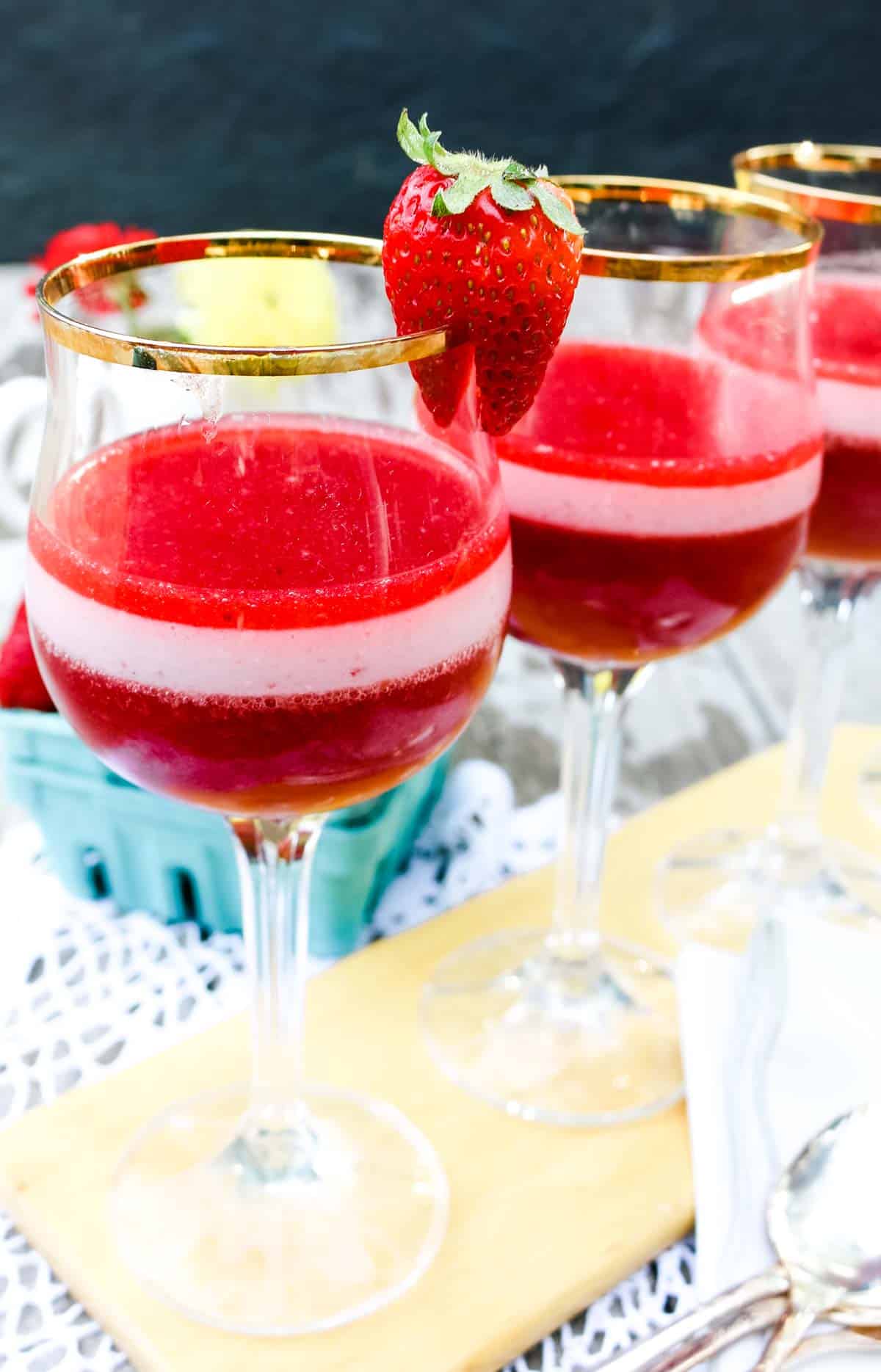 Layered homemade strawberry and cream dessert in wine glasses with fresh strawberries as garnish.