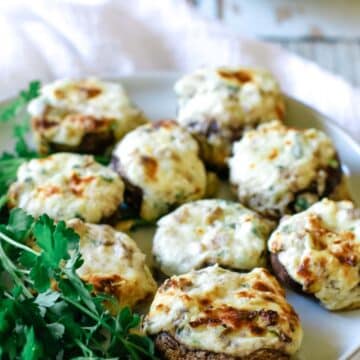 A plate of stuffed mushrooms with parsley garnish on the side.