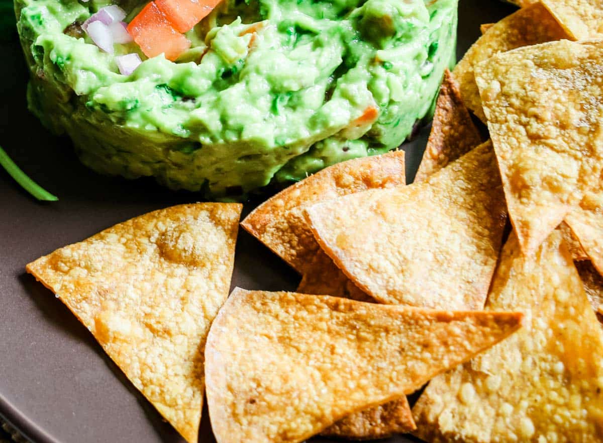 baked homemade tortilla chips and guacamole on a plate