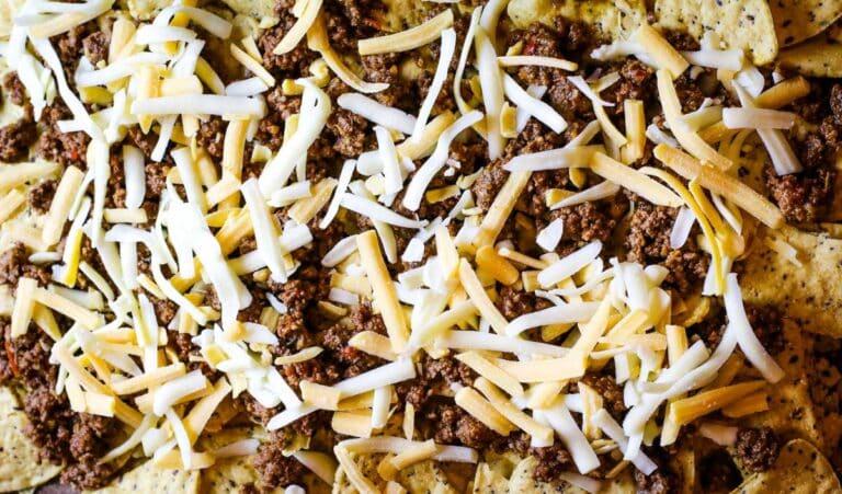 layering cheese and taco meat over tortilla chips