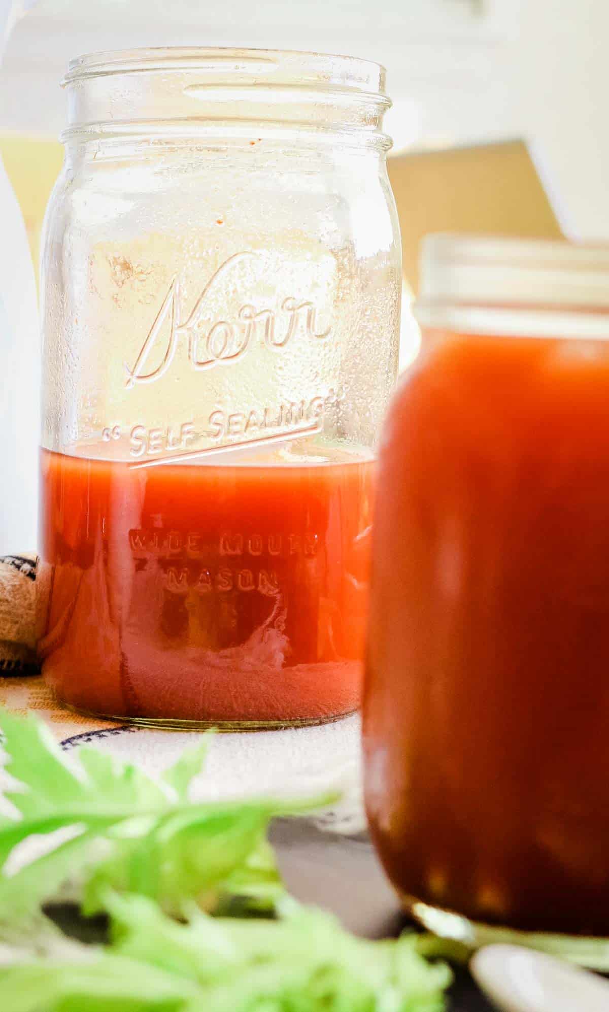 tomato juice in 2 mason jars with celery leaves on side