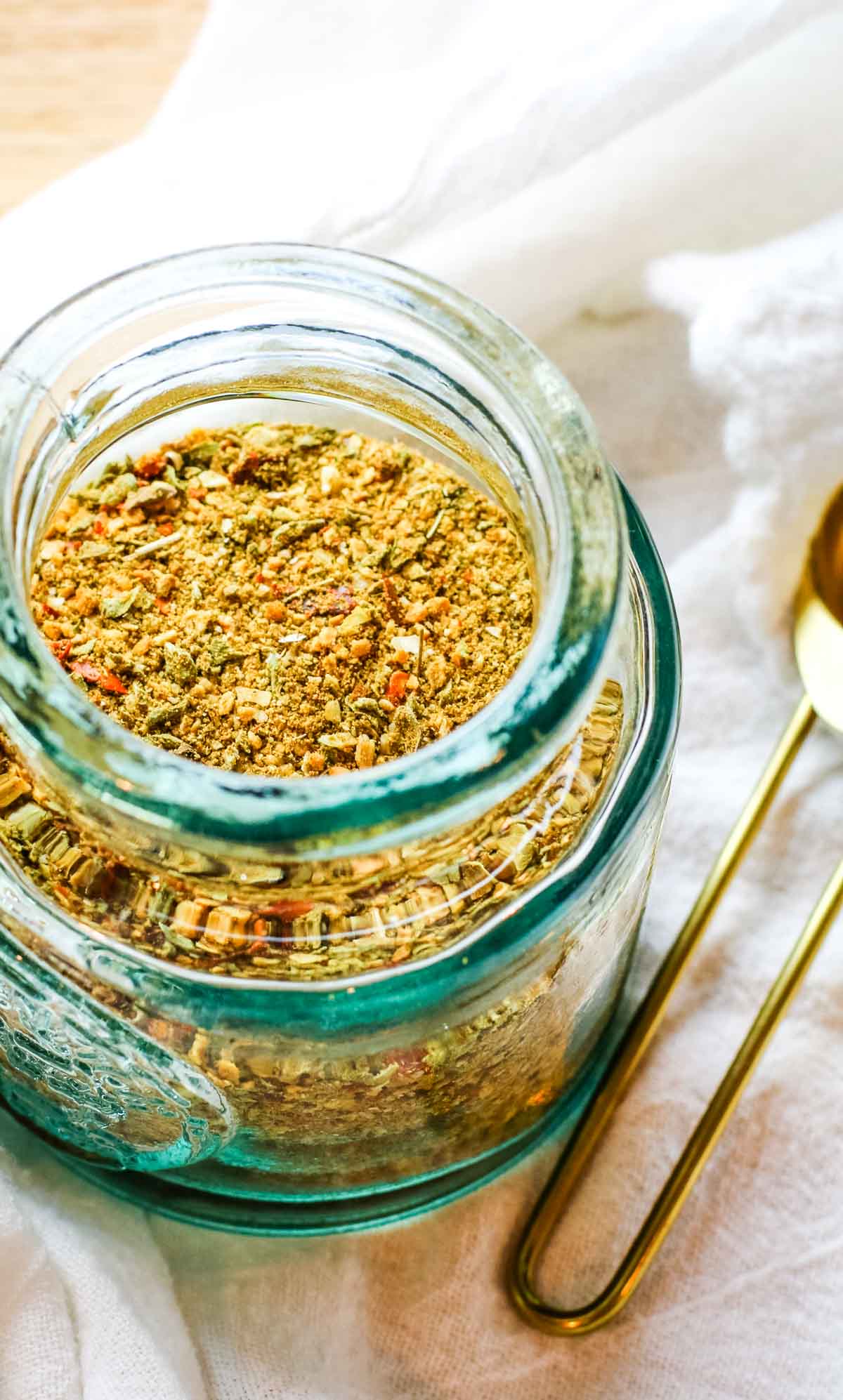 taco seasoning in a small blue jar with tablespoon measuring spoon on the side