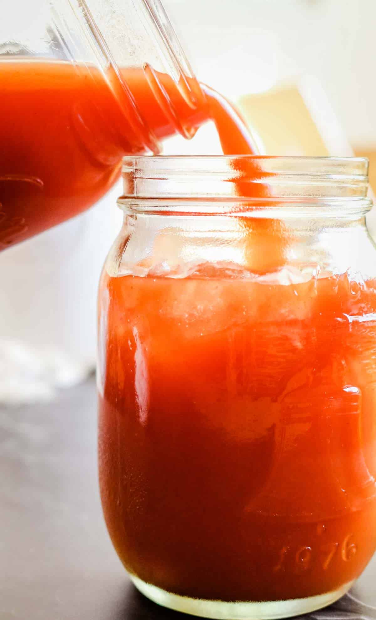 tomato juice poured from one mason jar to another