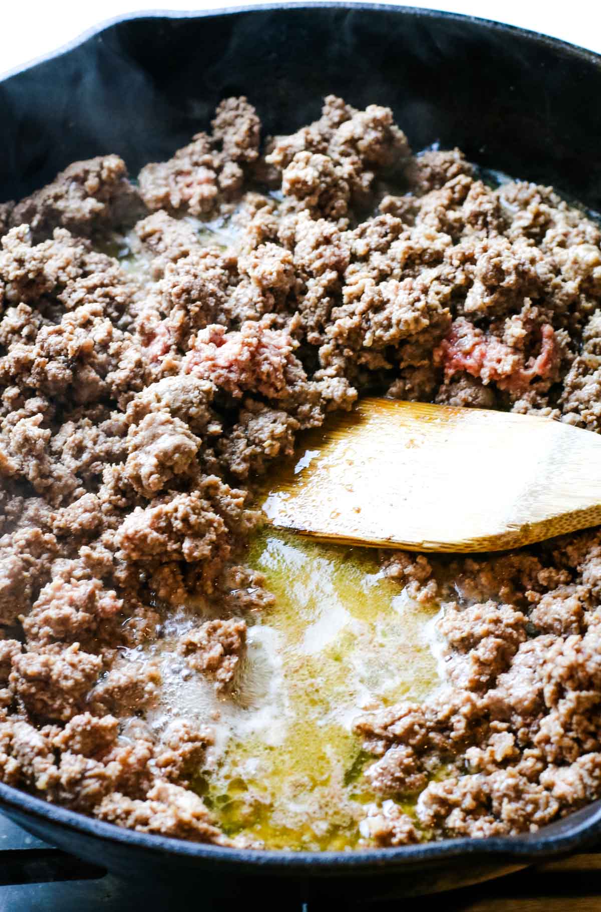 Browning ground beef and spoon exposing excess fat in meat