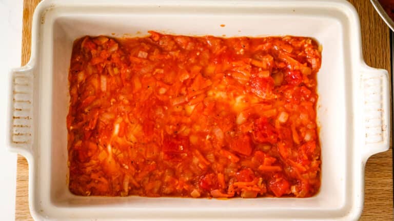 baking dish with tomato sauce spread out