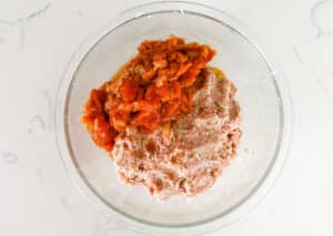 tomato sauce added to meat mixture in glass bowl