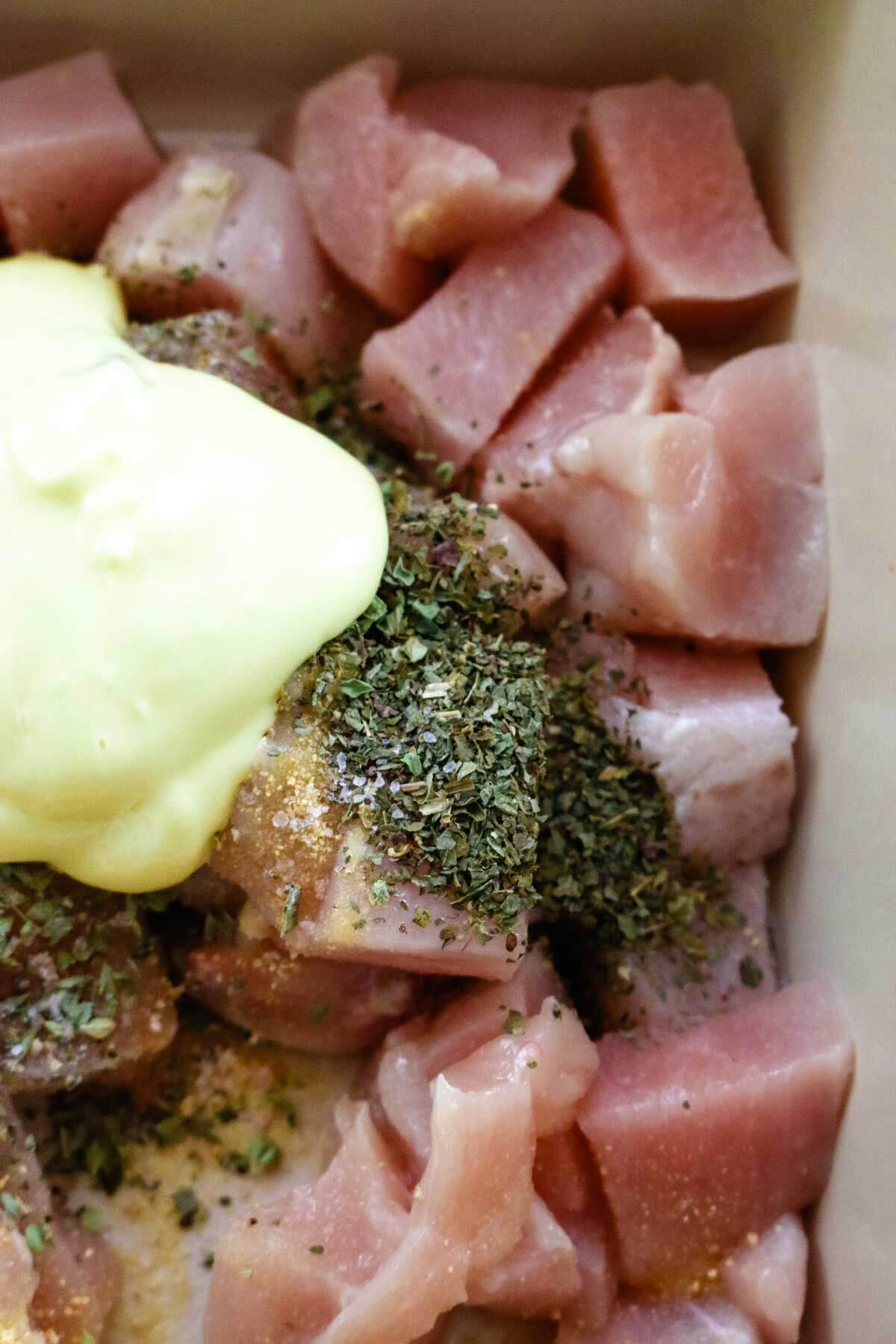 raw chicken with herbs and mayonnaise in casserole dish