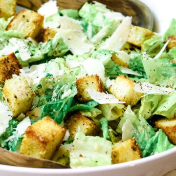 white bowl with caesar salad on top of white kitchen towel