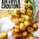 text overlay that says Air Fryer Croutons on a photo of croutons spilled out of jar on white towel.