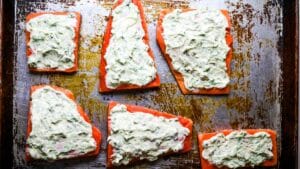 salmon fillets on baking sheet with mayo cream on top.