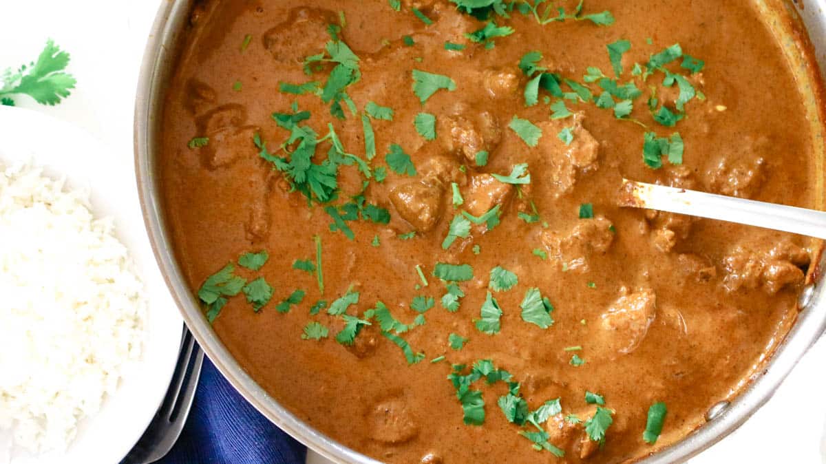 Butter chicken in a deep pan with cilantro garnish