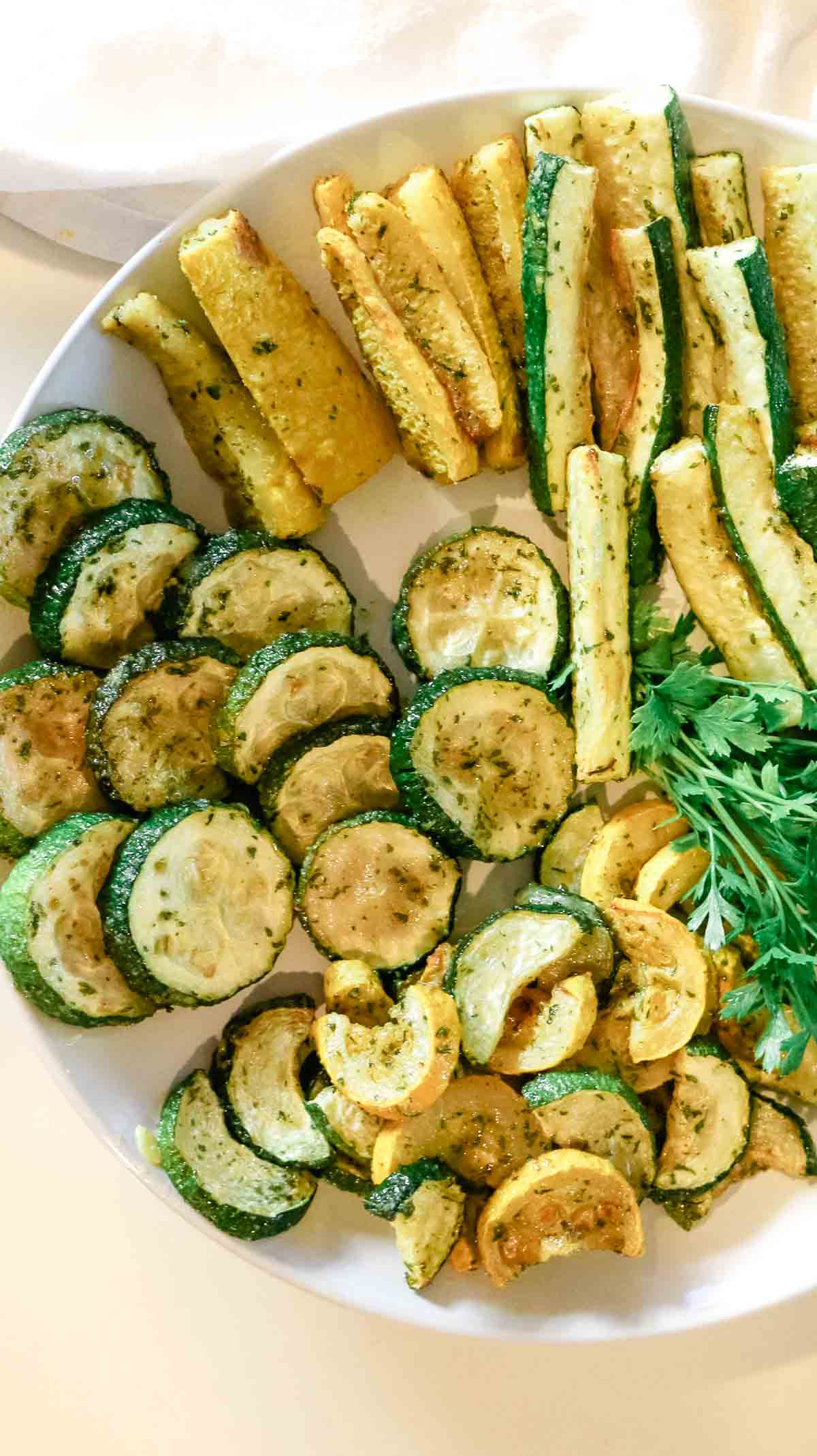 roasted zucchini rounds and zucchini fries on a white plate.