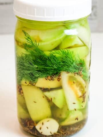 green tomatoes with fresh dill in mason jar.