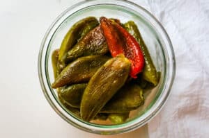 roasted and peeled jalapeno peppers in a jar.